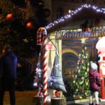 Wieczór, mieszkańcy stoją przed oświetloną chatką Mikołaja na mosińskim rynku